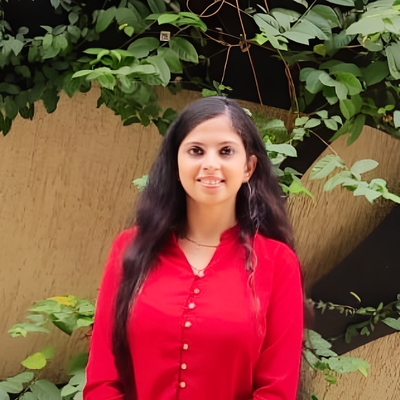 headshot of Anukriti: woman with brownish-black hair wearing a red shirt