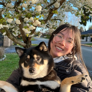 bingbing and her dog noodle in front of a blossoming tree