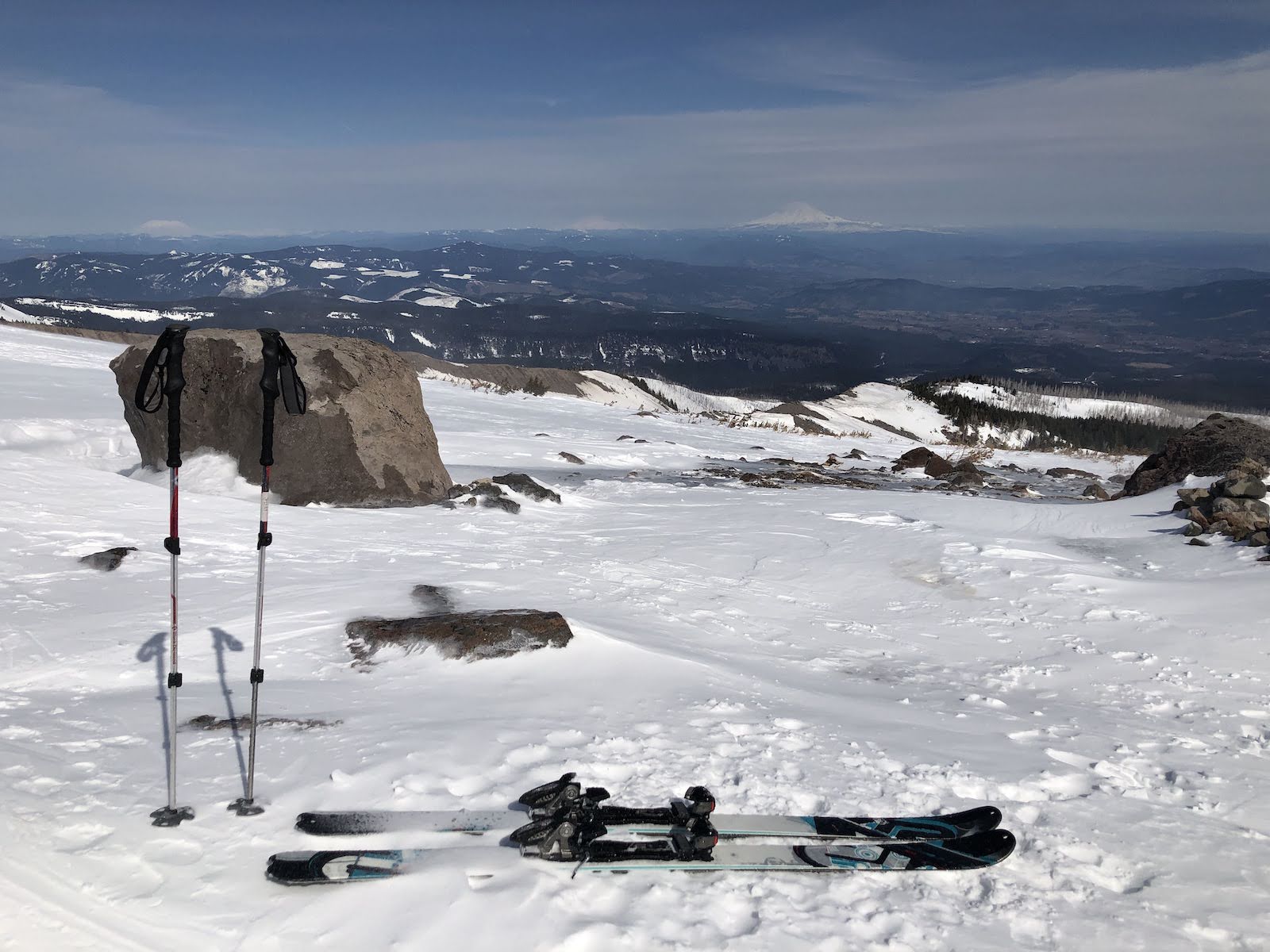 skis sit next to a pair of ski poles standing in the snow looking down from the Cooper Spur Shelter on Mt Hood towards Mt Adams
