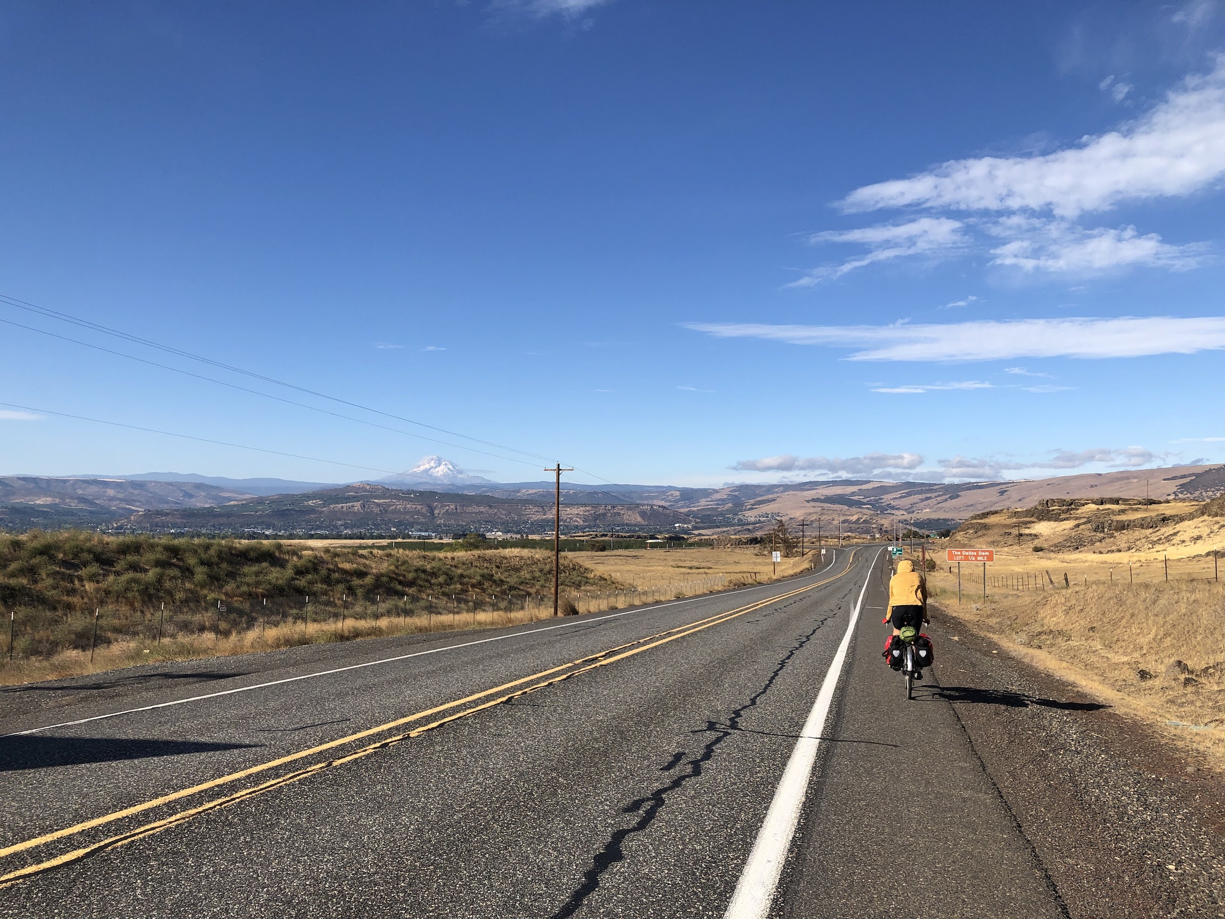 a man bikes on the shoulder of a single lane highway
