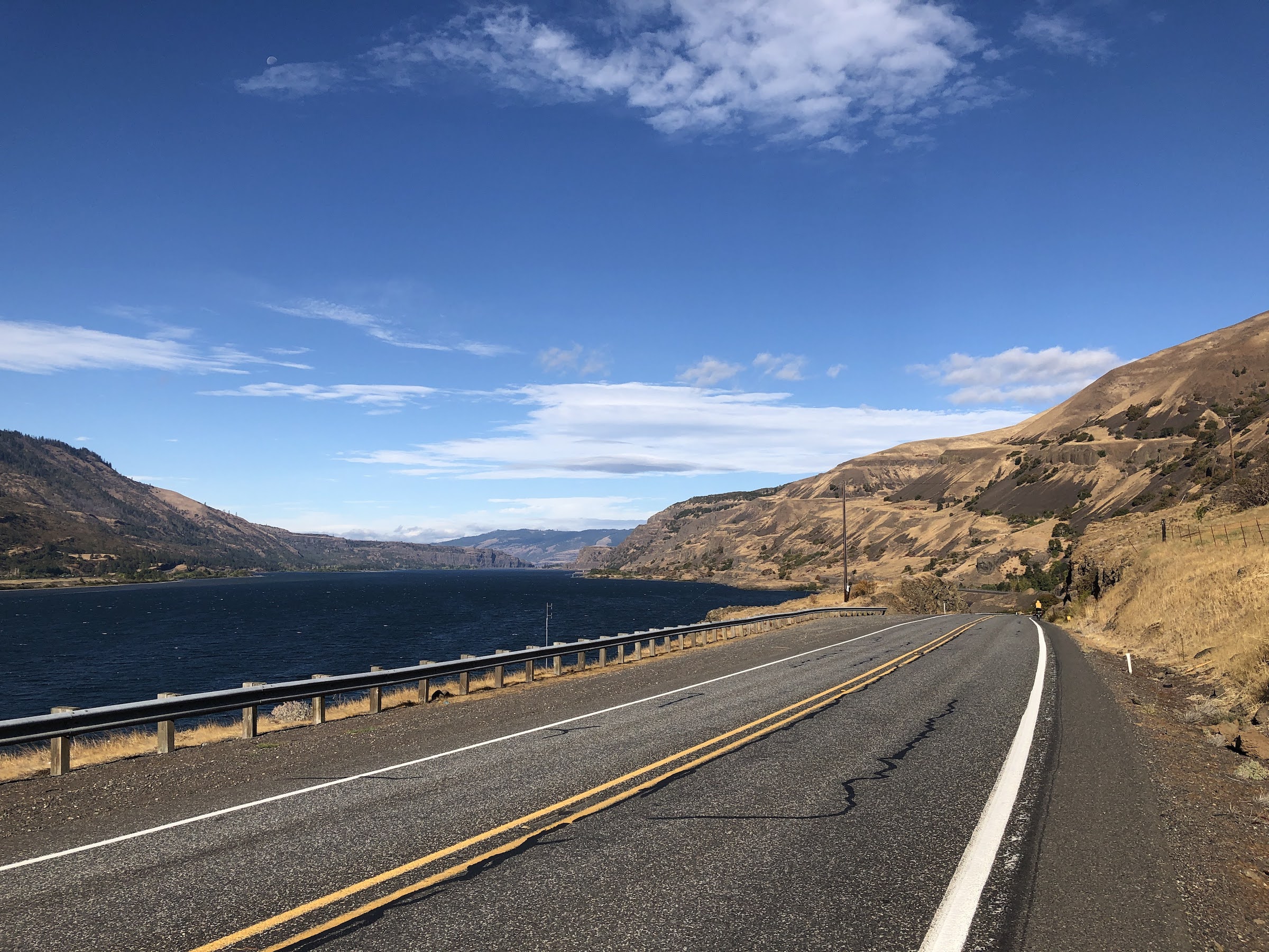 a road curves around the bend along a river
